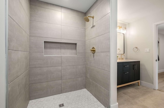 full bathroom featuring baseboards, tiled shower, and vanity