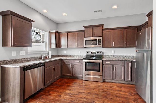 kitchen with stone countertops, dark wood-type flooring, a sink, visible vents, and appliances with stainless steel finishes