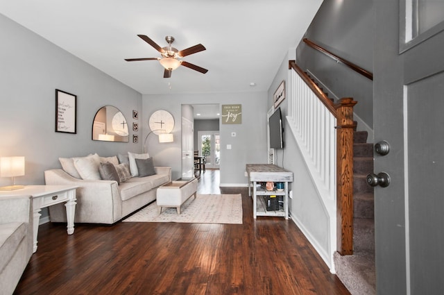 living area featuring ceiling fan, stairs, baseboards, and dark wood finished floors