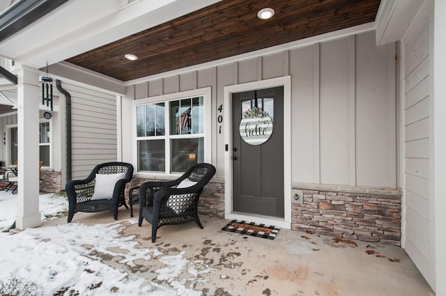 view of exterior entry featuring stone siding, a porch, and board and batten siding