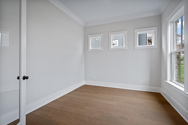 unfurnished room with ornamental molding, baseboards, and wood finished floors