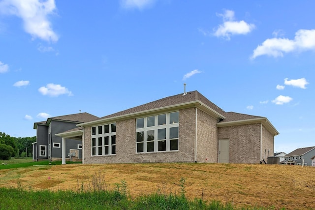 rear view of property with brick siding and a lawn