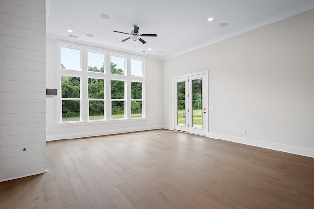 empty room with wood finished floors, a wealth of natural light, and baseboards