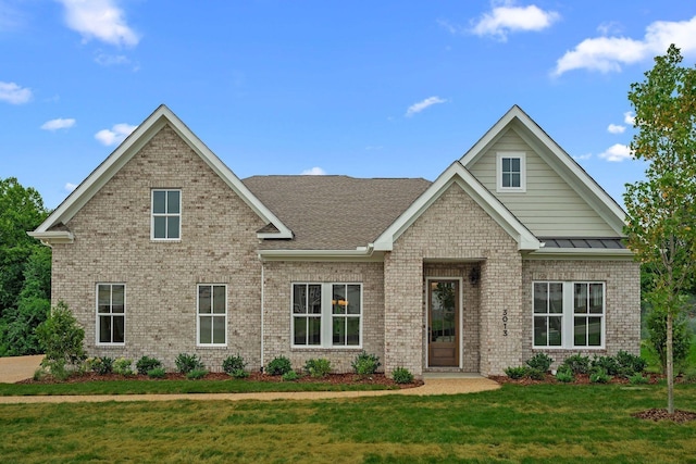 craftsman-style house with brick siding, a shingled roof, a front yard, a standing seam roof, and metal roof