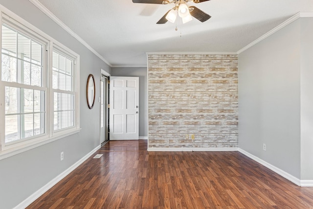 spare room with dark wood-style floors, ornamental molding, ceiling fan, a textured ceiling, and baseboards