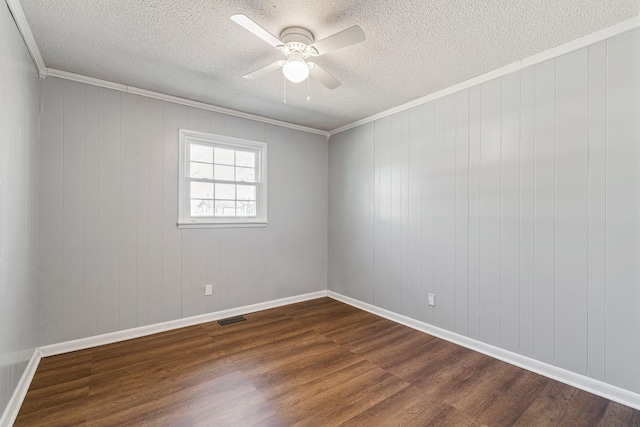 unfurnished room with baseboards, visible vents, a ceiling fan, ornamental molding, and dark wood-type flooring