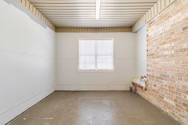 spare room with brick wall and unfinished concrete floors