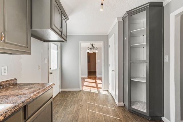 kitchen with dark wood-type flooring, ornamental molding, a textured ceiling, and baseboards