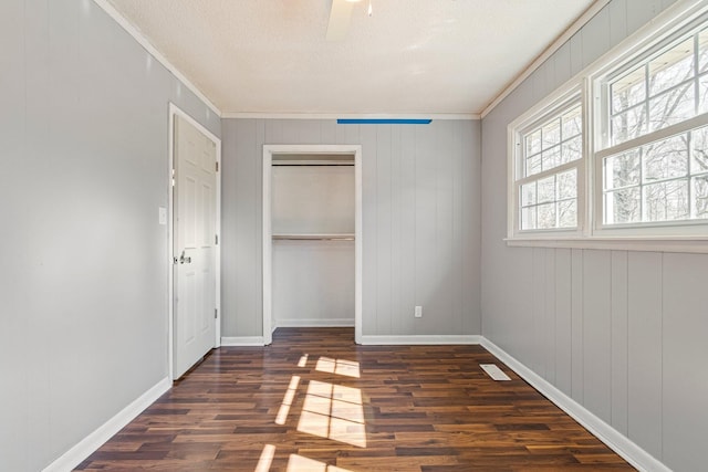 unfurnished bedroom with crown molding, a closet, dark wood finished floors, and baseboards