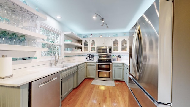 kitchen featuring a sink, light countertops, appliances with stainless steel finishes, open shelves, and tasteful backsplash