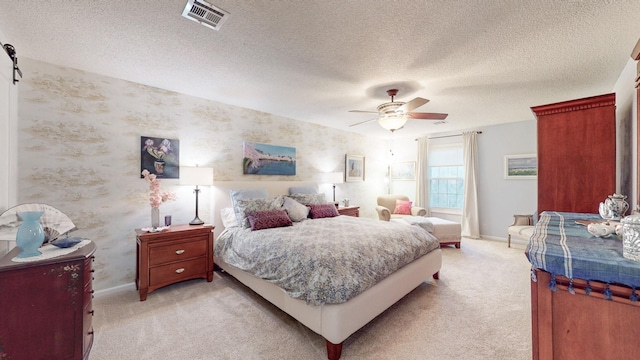 bedroom featuring wallpapered walls, baseboards, visible vents, light colored carpet, and a textured ceiling