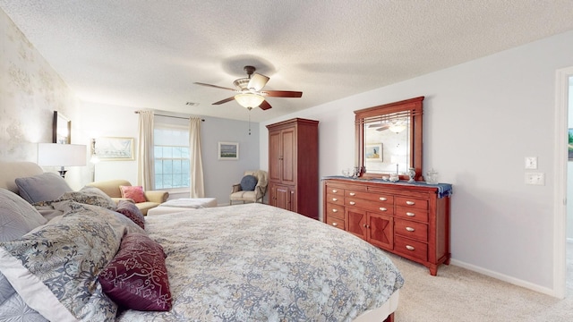 bedroom with a textured ceiling, light carpet, a ceiling fan, visible vents, and baseboards