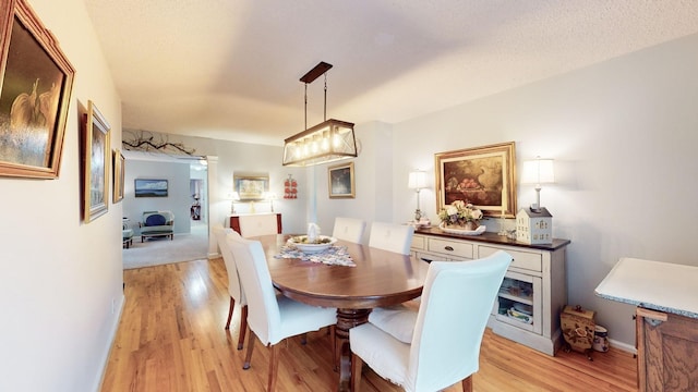 dining area with light wood-style floors, baseboards, and a textured ceiling