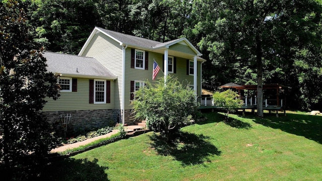 view of front of home with a shingled roof, a front yard, and a wooden deck