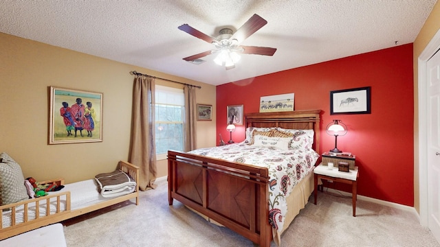bedroom with a ceiling fan, light carpet, a textured ceiling, and baseboards
