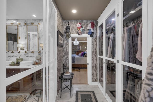 ensuite bathroom featuring marble finish floor, recessed lighting, connected bathroom, a sink, and wallpapered walls