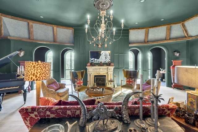 living area featuring arched walkways, a fireplace, a decorative wall, and an inviting chandelier