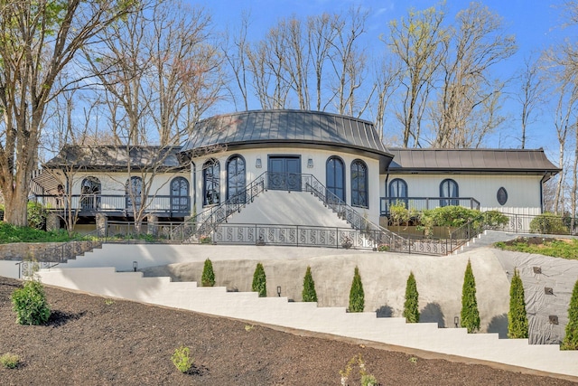 view of front of house with a standing seam roof, metal roof, and stairway