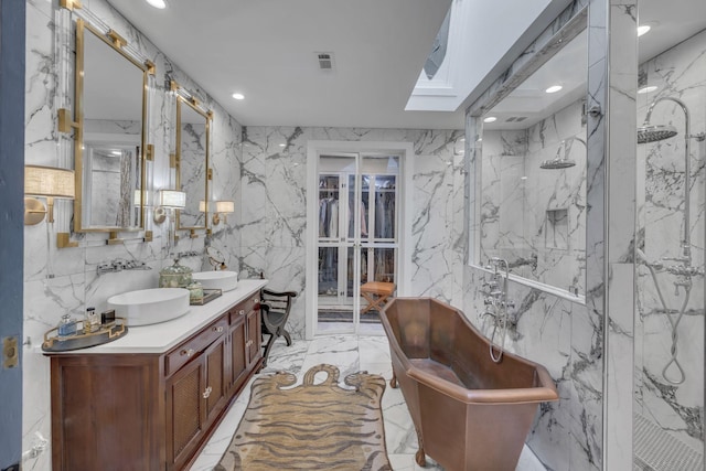 bathroom with marble finish floor, a marble finish shower, double vanity, a sink, and stone wall