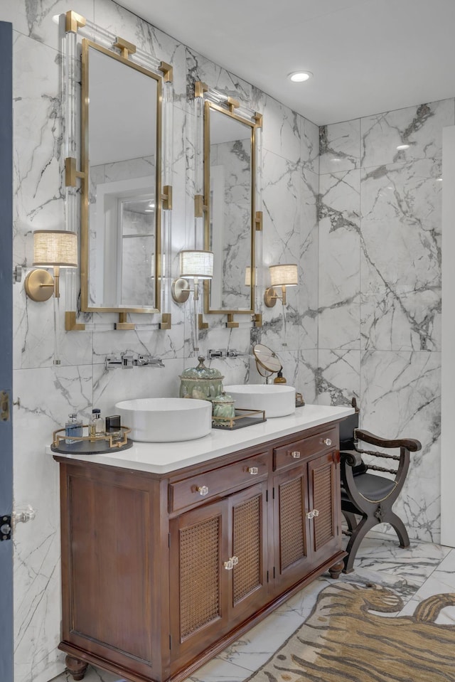 bathroom with double vanity, a sink, marble finish floor, and stone wall