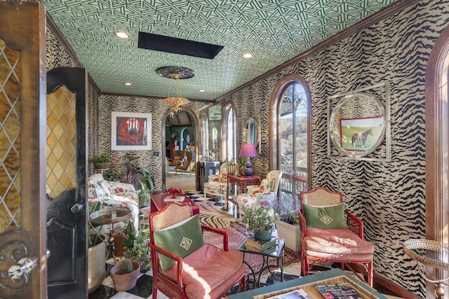 living area with arched walkways, crown molding, and wallpapered walls