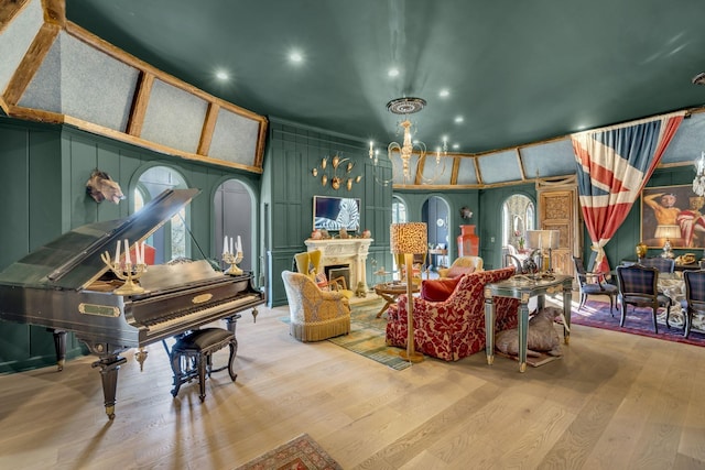 interior space featuring a fireplace, wood finished floors, an inviting chandelier, and a decorative wall