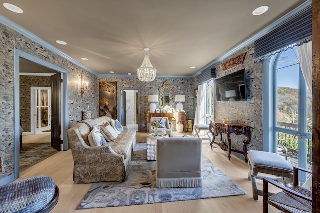 living area with crown molding, light wood-style floors, a chandelier, and plenty of natural light