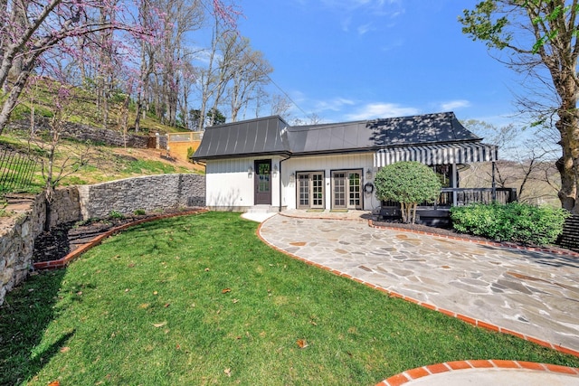 back of property featuring fence, metal roof, and a yard