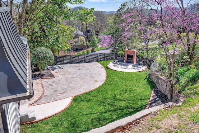 view of yard featuring a patio area, fence, and an outdoor fireplace