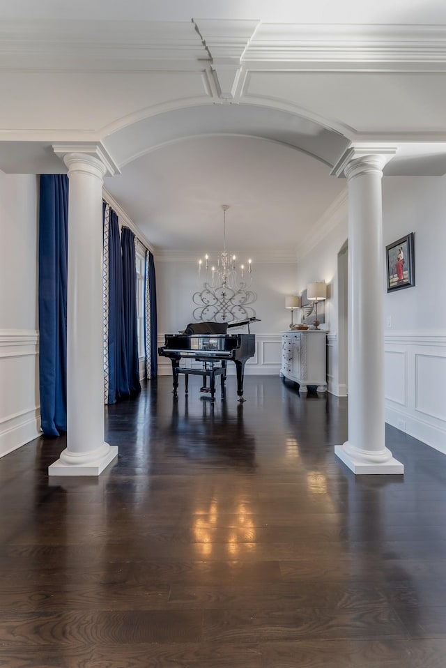 unfurnished dining area featuring arched walkways, dark wood finished floors, decorative columns, and a decorative wall