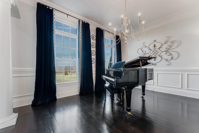 living area with a chandelier, a decorative wall, dark wood-type flooring, ornamental molding, and wainscoting