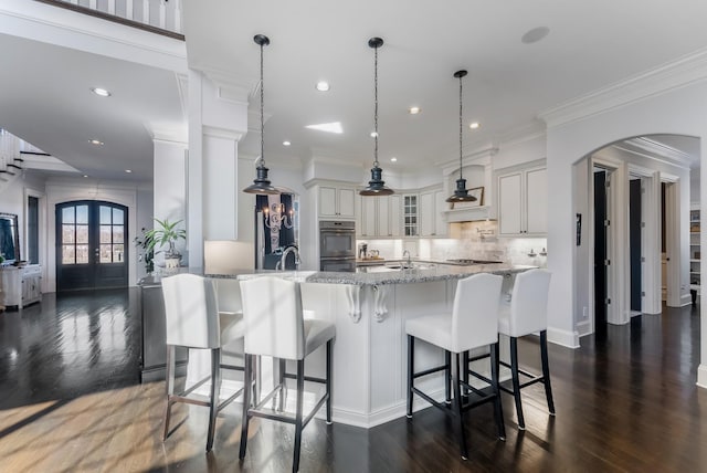 kitchen with arched walkways, pendant lighting, french doors, glass insert cabinets, and white cabinetry