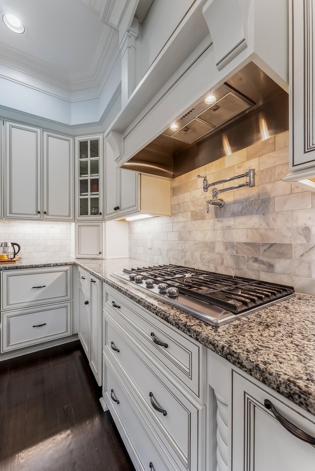 kitchen with white cabinetry, custom range hood, stainless steel gas stovetop, and glass insert cabinets