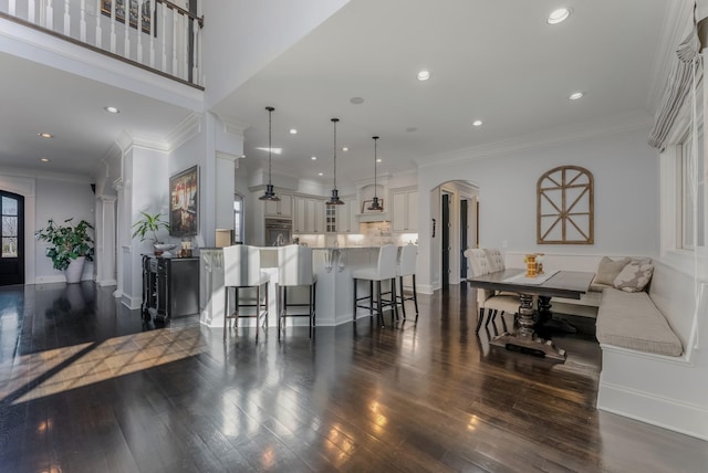 interior space with arched walkways, ornamental molding, dark wood finished floors, and recessed lighting