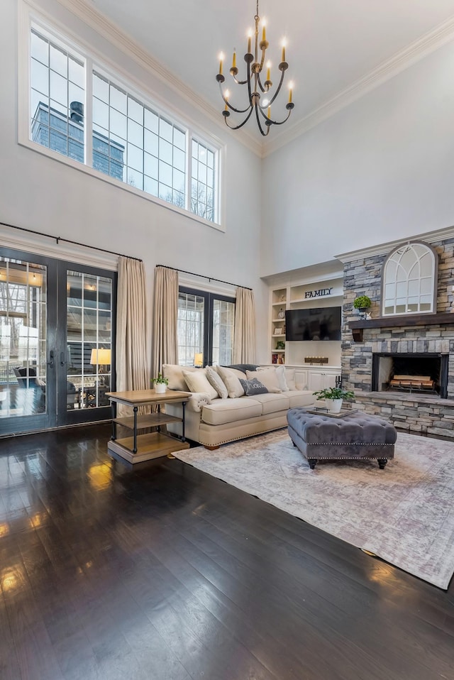 living room featuring a stone fireplace, dark wood finished floors, crown molding, and french doors