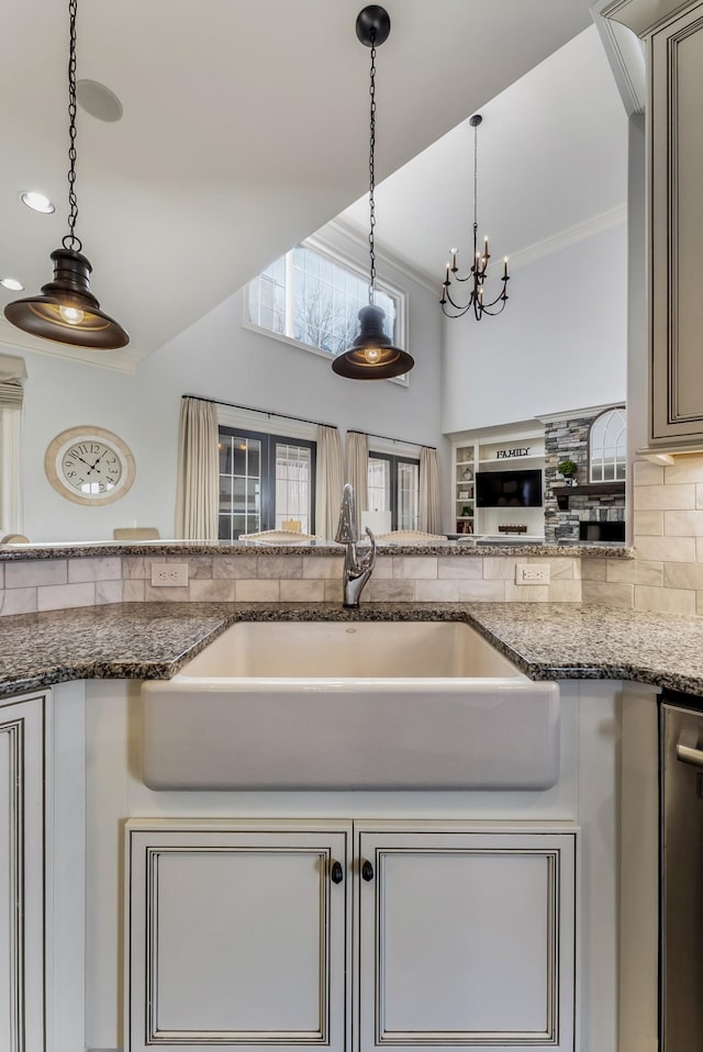 kitchen with decorative backsplash, a sink, decorative light fixtures, and crown molding