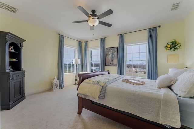 bedroom with light carpet, ceiling fan, visible vents, and baseboards