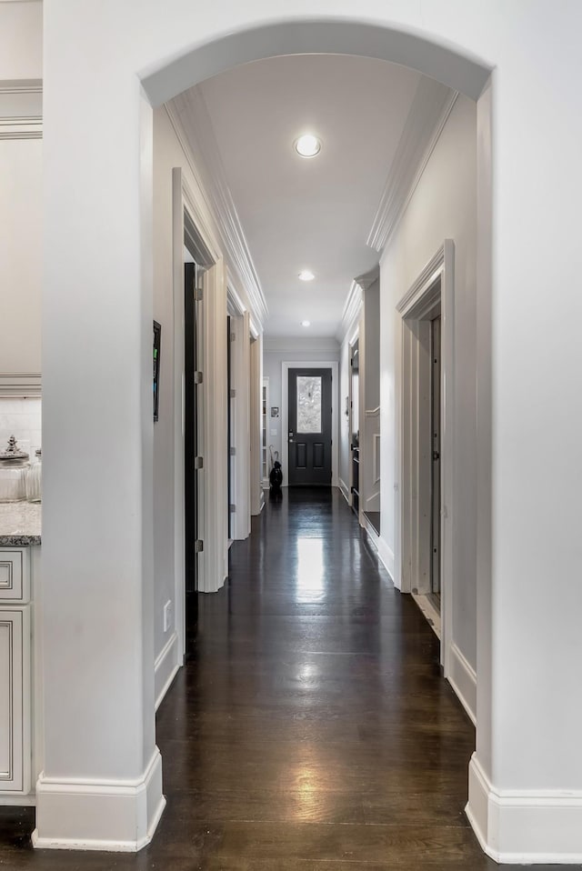 corridor with baseboards, arched walkways, dark wood-style floors, crown molding, and recessed lighting