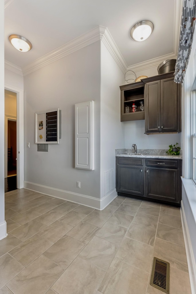 bar featuring light tile patterned flooring, a sink, visible vents, baseboards, and ornamental molding