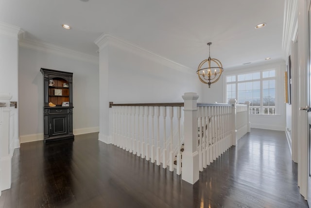 corridor featuring recessed lighting, a notable chandelier, dark wood-type flooring, baseboards, and ornamental molding