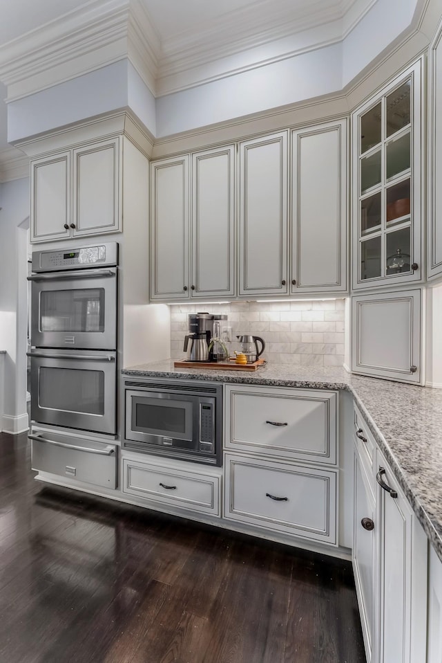 interior space with stainless steel appliances, glass insert cabinets, a warming drawer, and ornamental molding