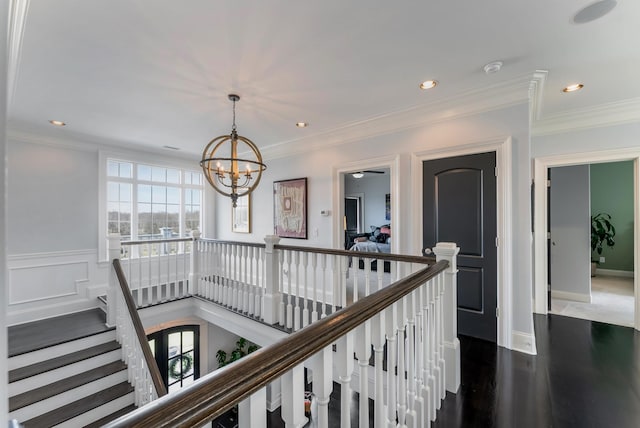 corridor with dark wood-style flooring, crown molding, recessed lighting, an inviting chandelier, and an upstairs landing