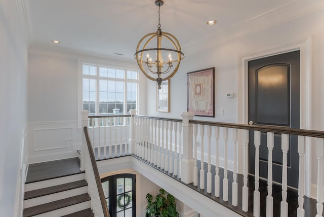 stairs with a wainscoted wall, a notable chandelier, crown molding, and recessed lighting