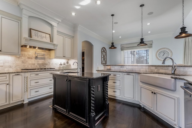 kitchen with arched walkways, a sink, hanging light fixtures, dishwasher, and dark stone countertops