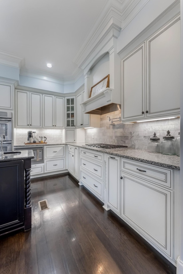 kitchen with ornamental molding, tasteful backsplash, glass insert cabinets, and white cabinetry