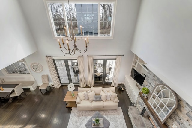 living room with a chandelier, dark wood-style floors, and a towering ceiling