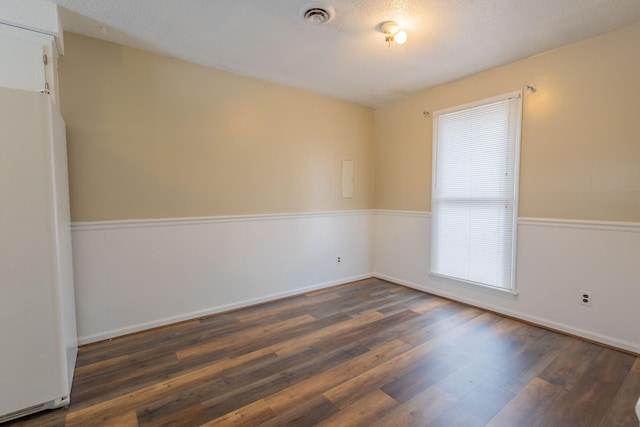 spare room featuring visible vents and dark wood-style flooring