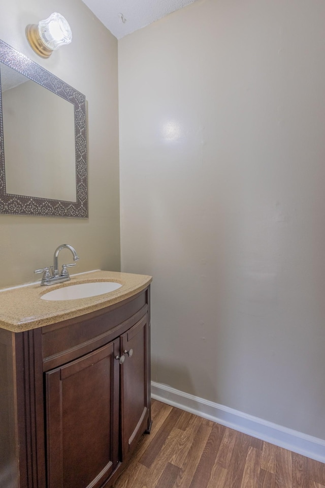 bathroom featuring baseboards, wood finished floors, and vanity