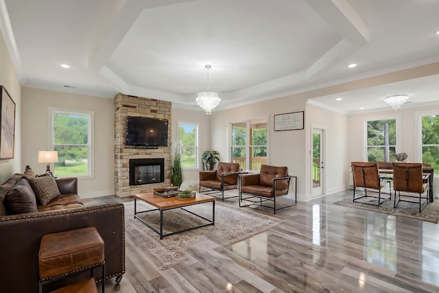 living room featuring a healthy amount of sunlight, a fireplace, a chandelier, and a tray ceiling