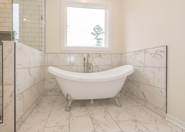 bathroom with tile walls, a freestanding tub, a wainscoted wall, and marble finish floor